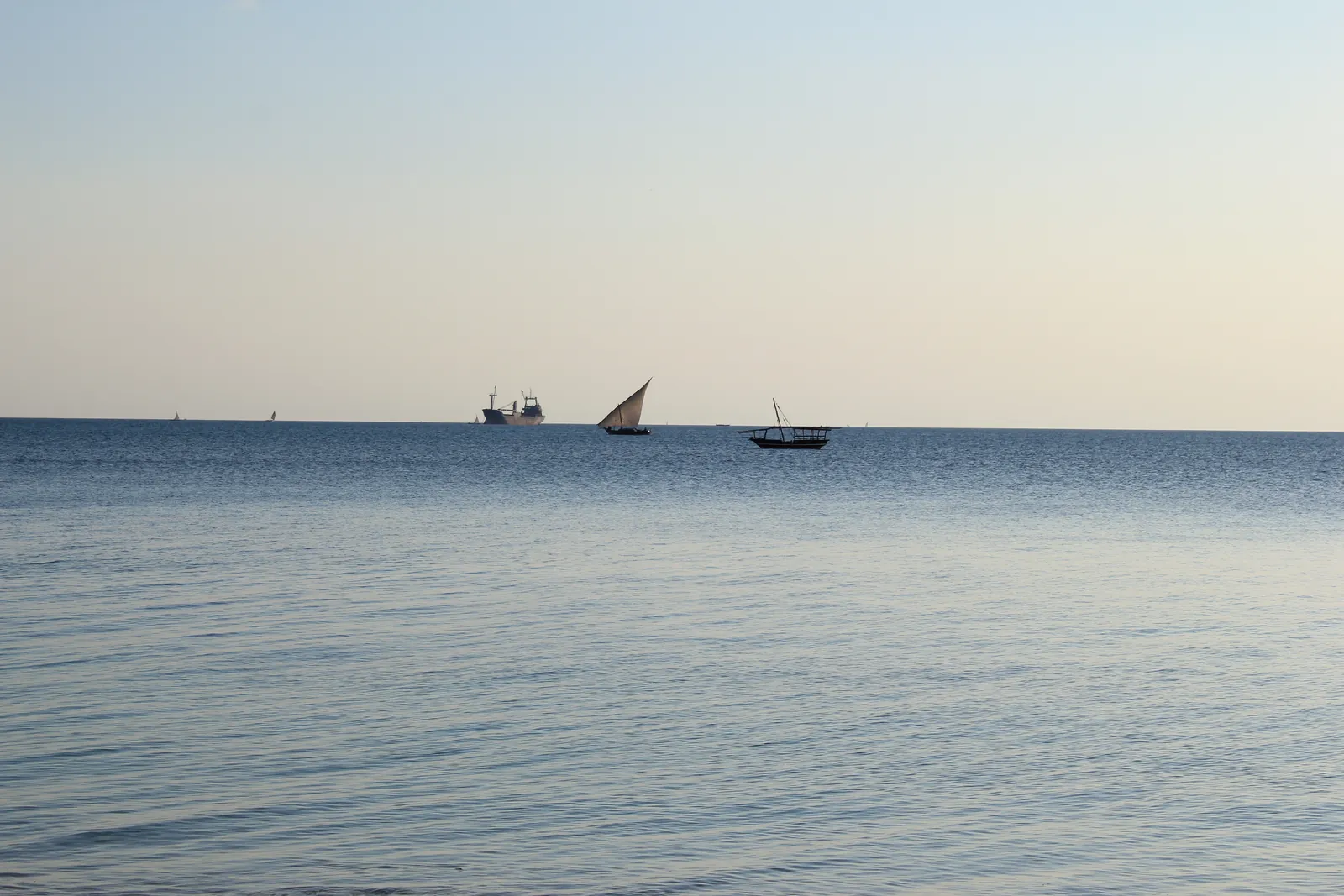 Boutre à voile et navires à l'horizon sur une mer calme au large de Zanzibar
