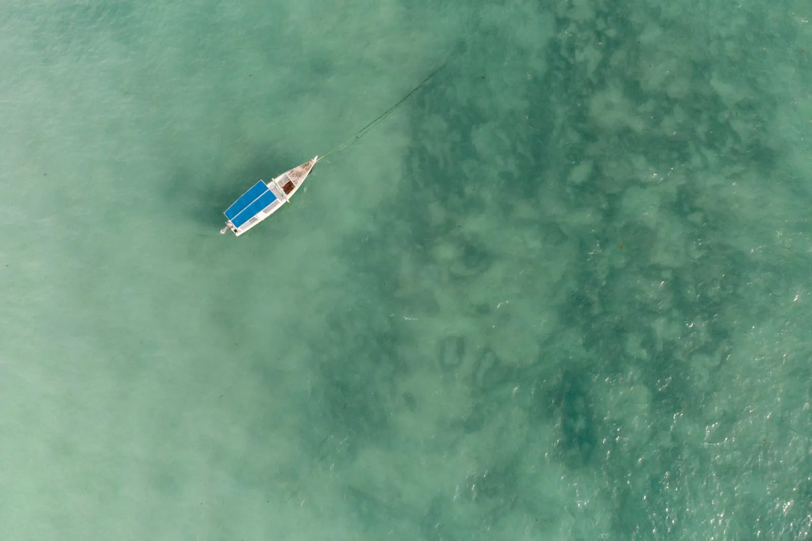 Embarcation traditionnelle vue du dessus dans une eau turquoise peu profonde à Zanzibar