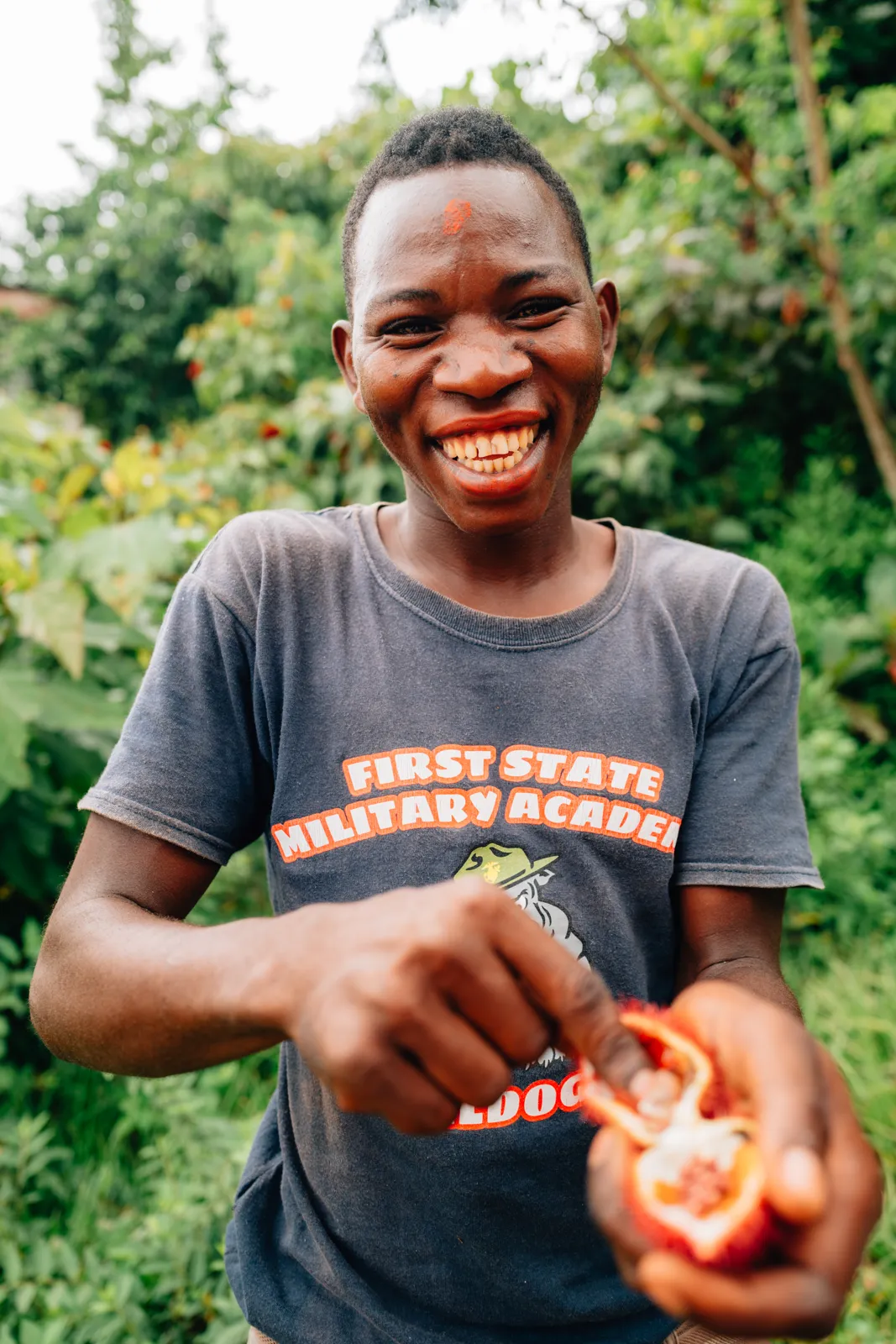 Jeune homme souriant montrant l'intérieur d'un fruit frais.