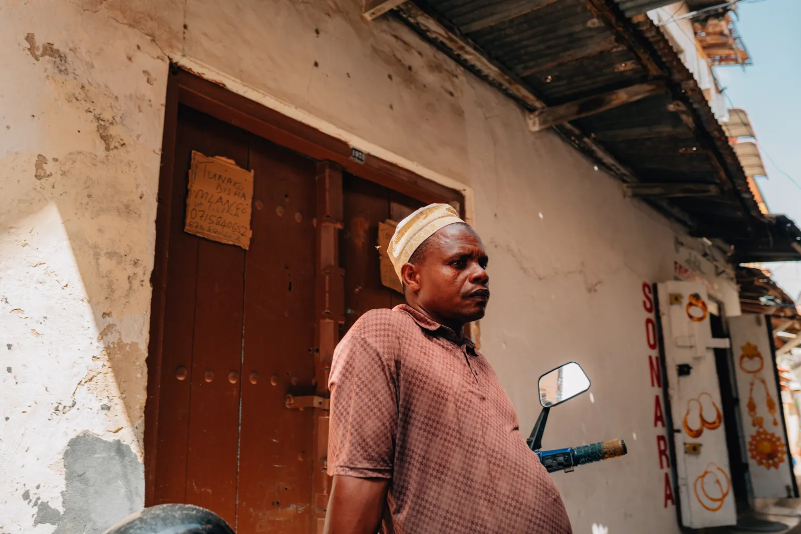 Un homme swahili portant une calotte dans une ruelle de village.
