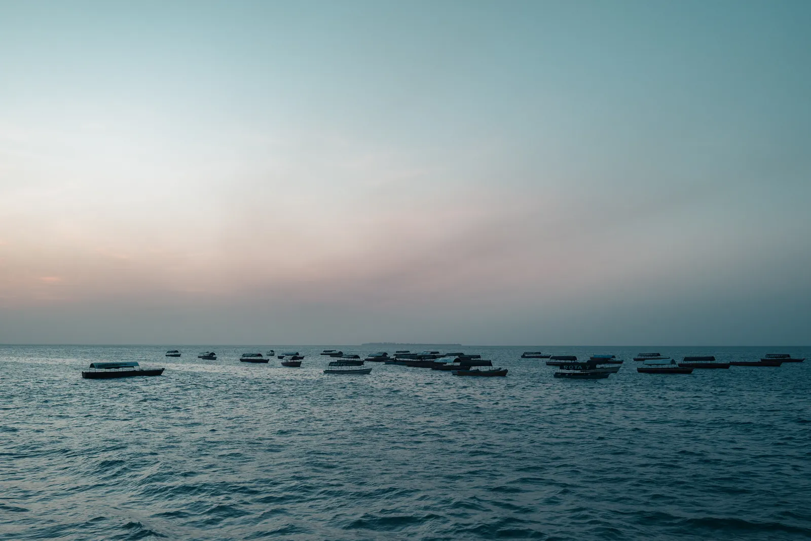 Bateaux en bois amarrés au large de Stone Town au coucher du soleil